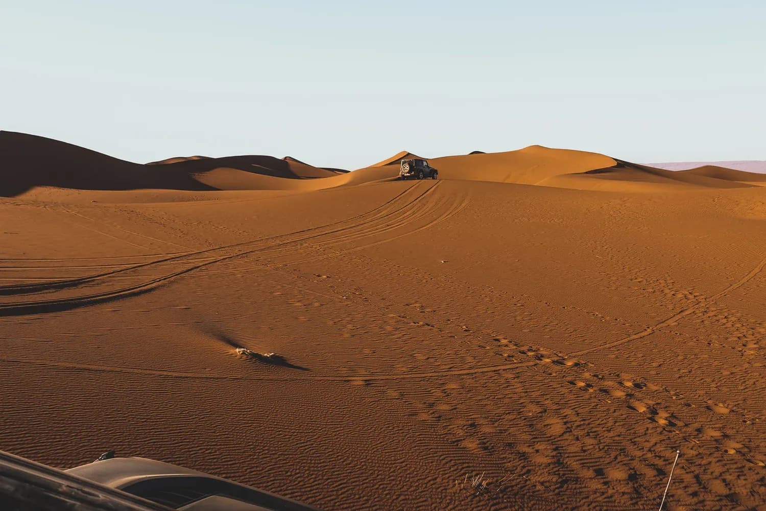 4x4 vehicle cresting a sand dune in Erg Chigaga, Moroccan Sahara