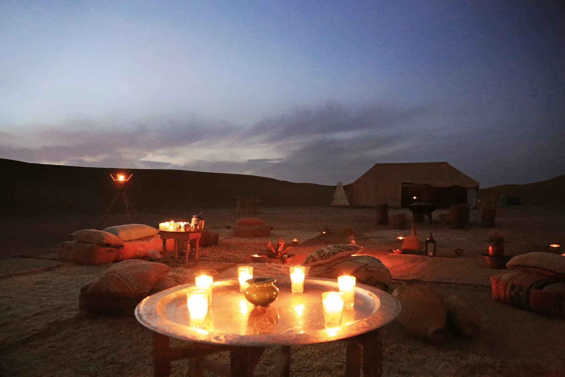 A low table of candles and a tea tray at dusk in the Agafay desert